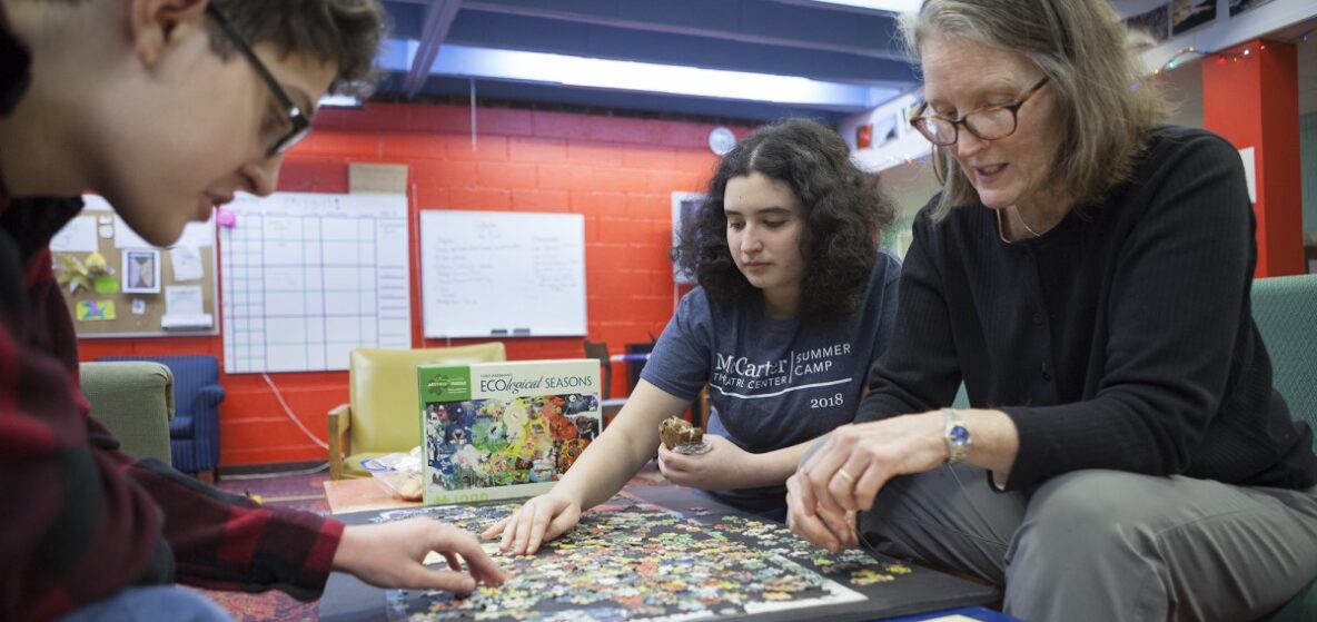 Two teens and adult working on a puzzle